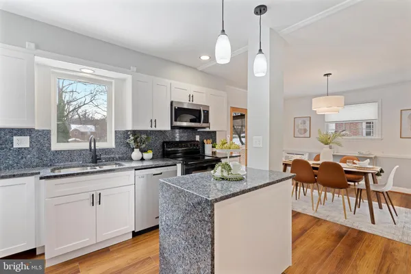 a kitchen with granite countertop a stove a sink a dining table and chairs