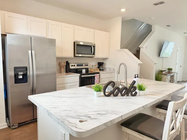 a kitchen with stainless steel appliances a sink a microwave a refrigerator a stove and white cabinets