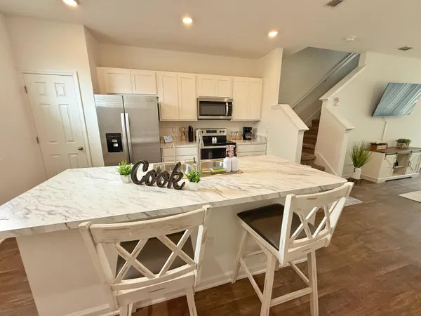 a kitchen with stainless steel appliances kitchen island granite countertop a kitchen island and chairs in it