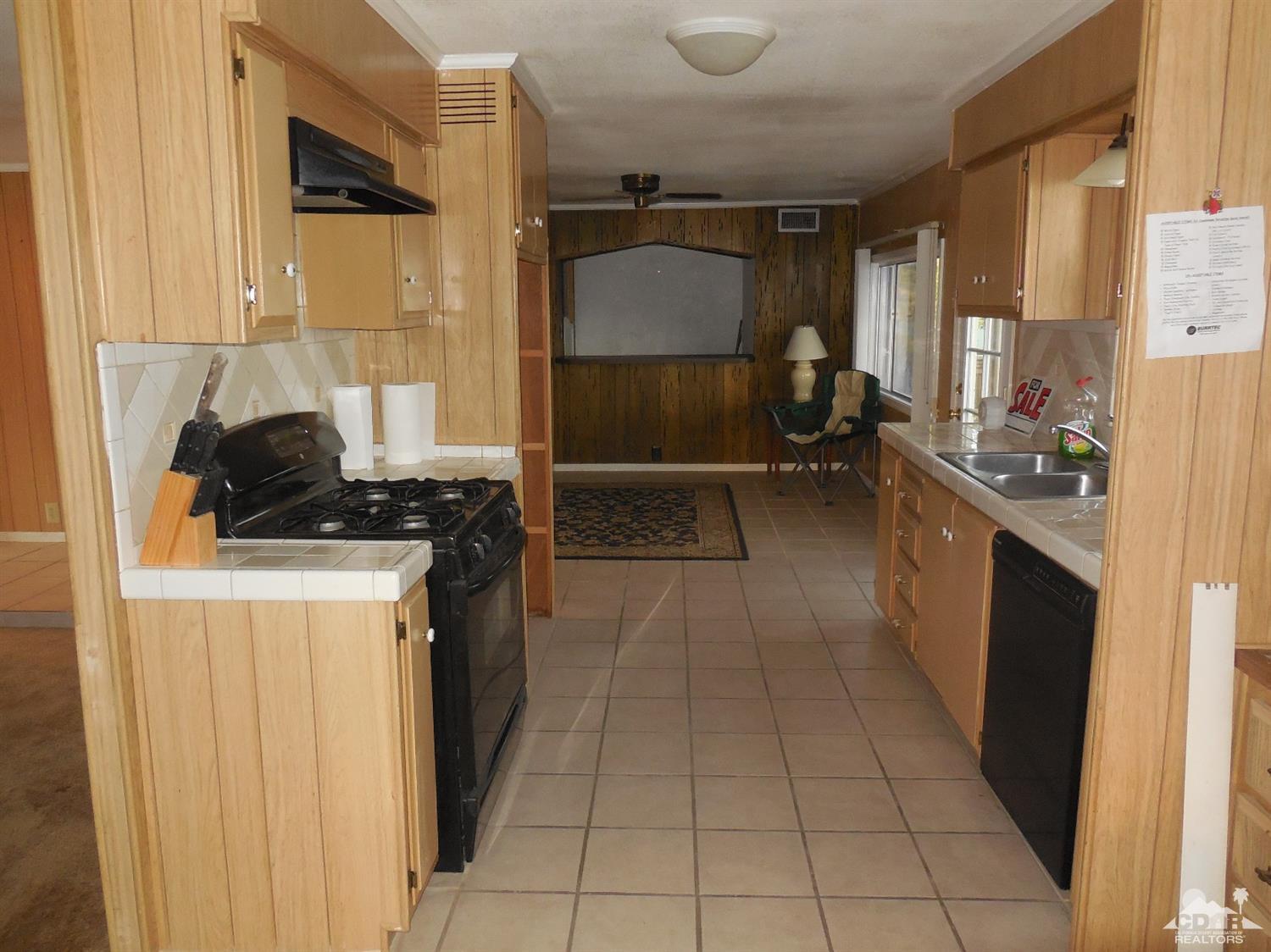 16820 Sunrise Road Desert Hot Springs, CA 92241 - Photo 6 of 19 a kitchen with a refrigerator a stove and a cabinets