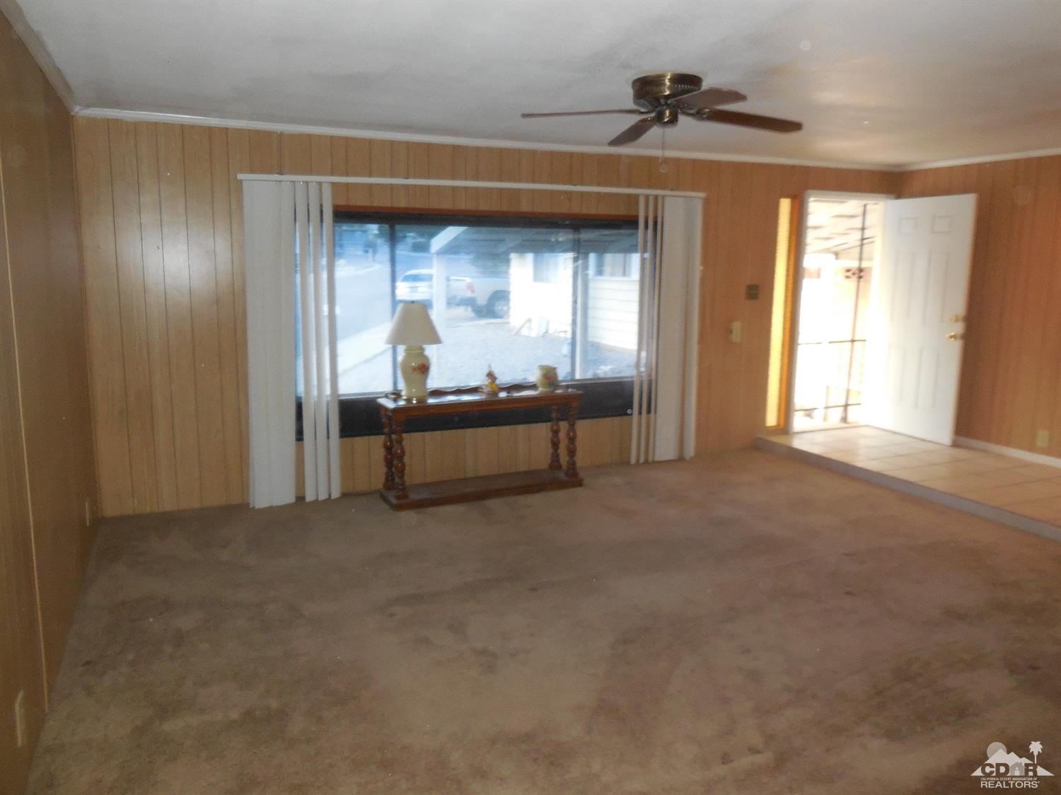 16820 Sunrise Road Desert Hot Springs, CA 92241 - Photo 7 of 19 a view of an empty room with a fireplace and a window