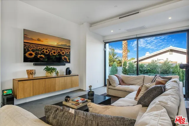 a living room with furniture a flat screen tv and a floor to ceiling window
