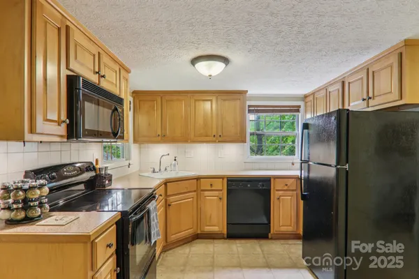 a kitchen with stainless steel appliances granite countertop a sink stove refrigerator and cabinets