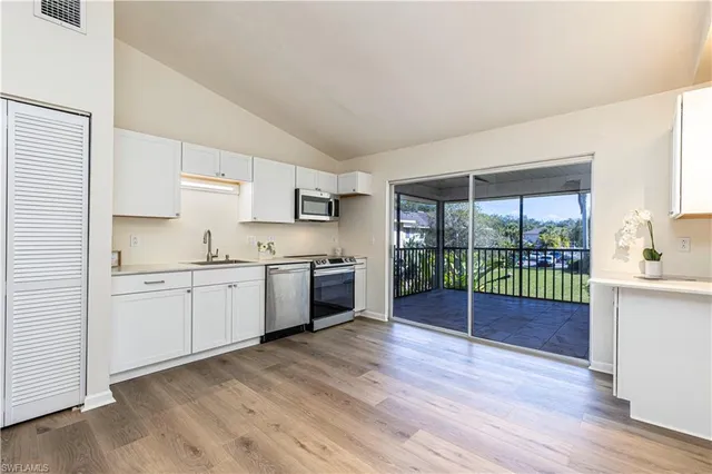 a kitchen with granite countertop a sink cabinets and wooden floor