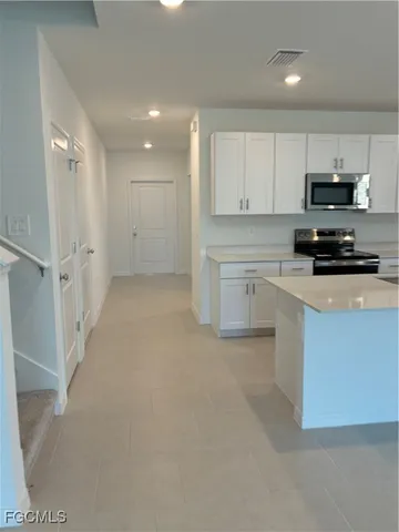 a kitchen with stainless steel appliances a refrigerator a stove a sink and white cabinets