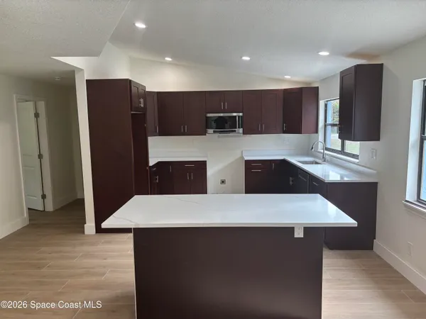 a large kitchen with kitchen island a sink and a refrigerator