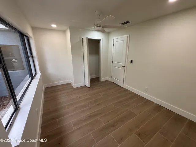 a view of an empty room with wooden floor and a window