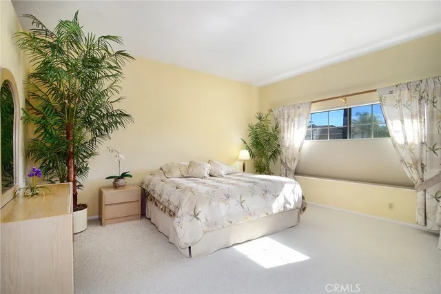 a bedroom with a large bed and a potted plant