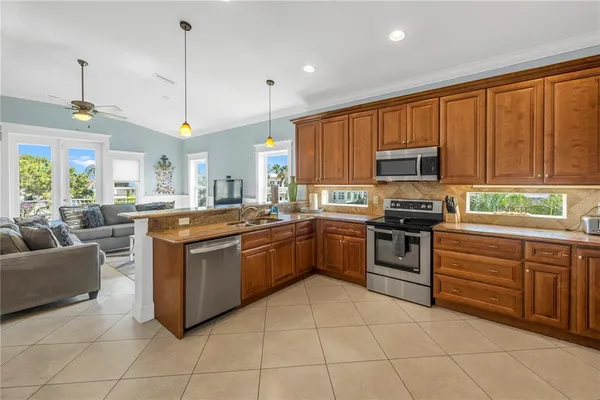 a kitchen with stainless steel appliances granite countertop a stove top oven a sink dishwasher and a refrigerator with wooden cabinets