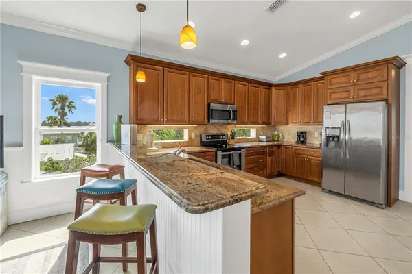 a kitchen with kitchen island granite countertop wooden cabinets a counter top space a sink stainless steel appliances and a window