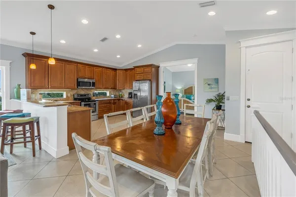 a kitchen with stainless steel appliances granite countertop a sink a stove a dining table and chairs