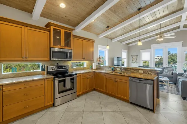 a kitchen with stainless steel appliances granite countertop stove top oven a sink dishwasher a dining table and chairs with wooden floor