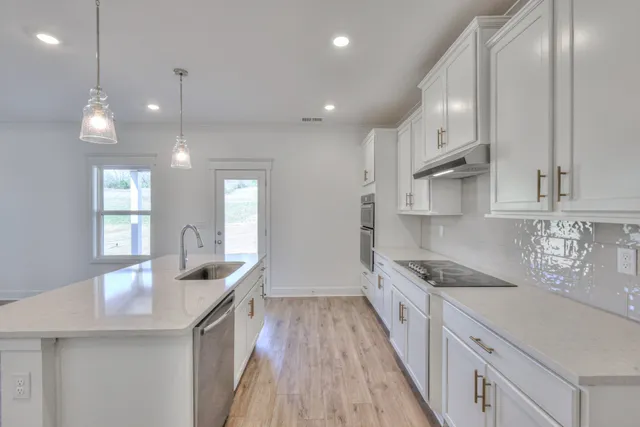 a kitchen with stainless steel appliances granite countertop a sink stove and cabinets