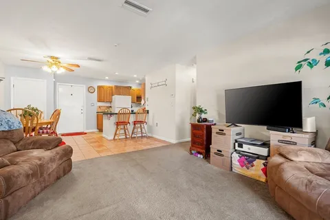 a kitchen with stainless steel appliances kitchen island granite countertop dining table chairs and a refrigerator