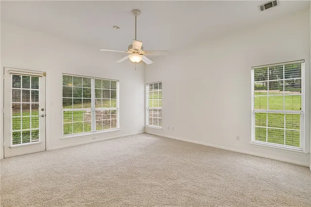 an empty room with windows chandelier fan and windows