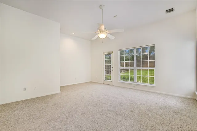 an empty room with a window and a ceiling fan