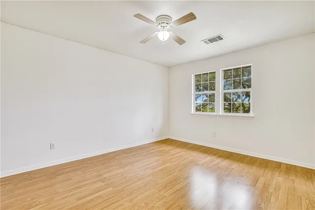 an empty room with a window and a ceiling fan