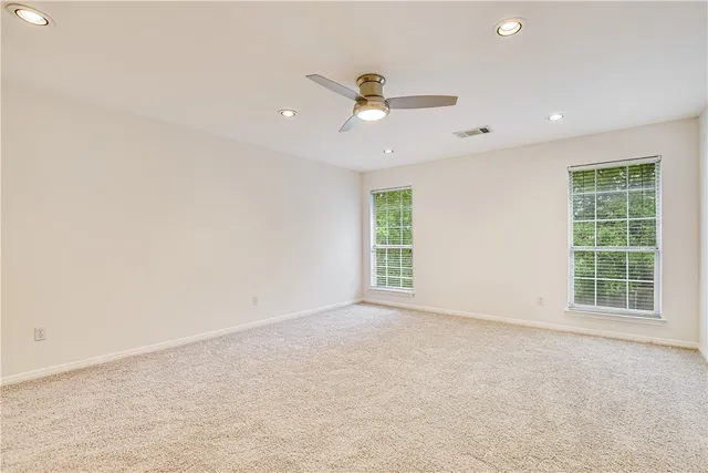 an empty room with windows and ceiling fan