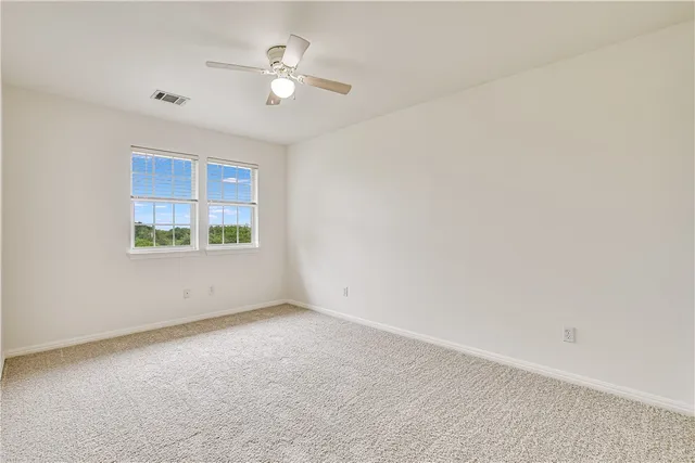 an empty room with windows and fan