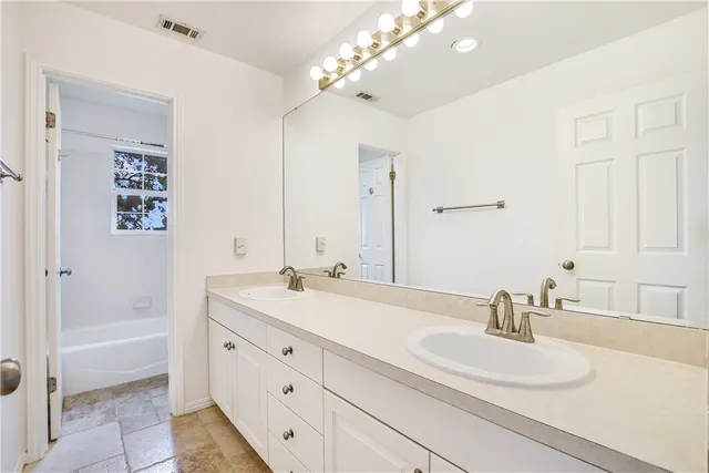 a bathroom with a sink double vanity granite tub and a mirror