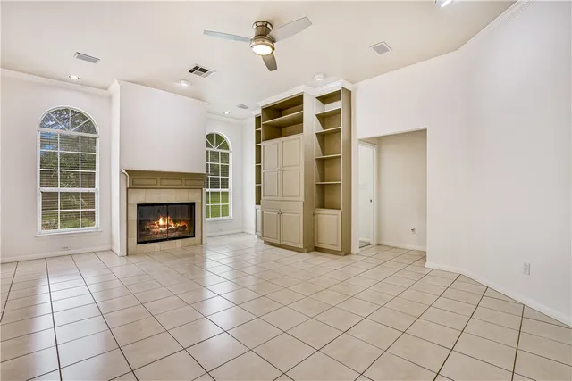 a view of a livingroom with a fireplace a ceiling fan and windows