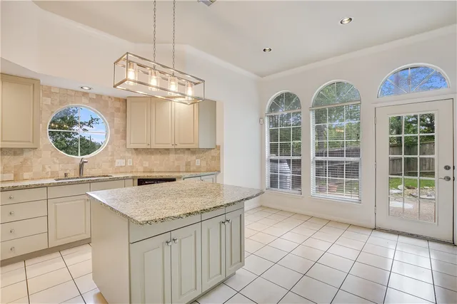 a view of a kitchen with granite countertop a sink window and cabinets