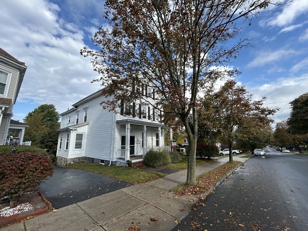 a view of a white house with a large tree