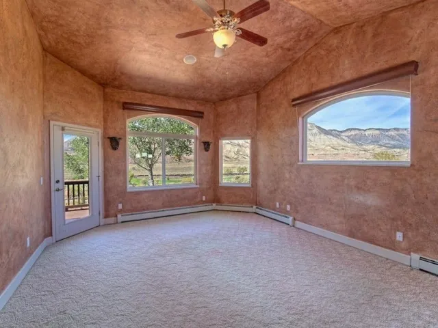 an empty room with windows and ceiling fan