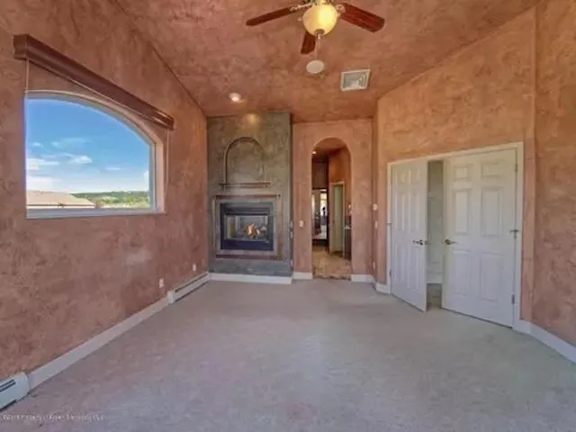 en empty room with chandelier fan and kitchen view