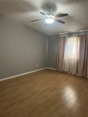 an empty room with windows and chandelier fan