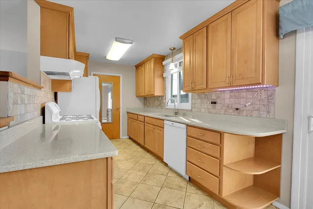 a kitchen with kitchen island granite countertop a sink a stove and cabinets
