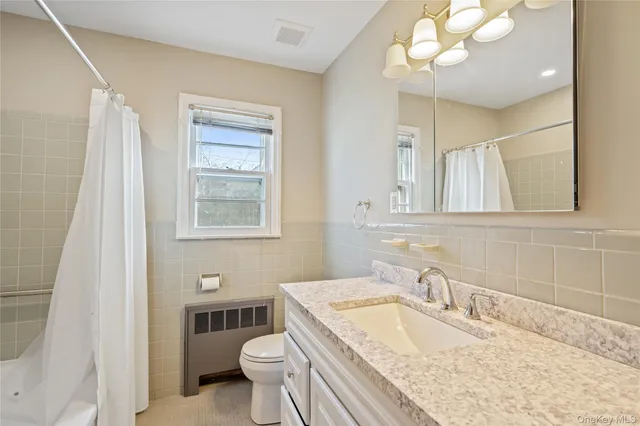 a bathroom with a granite countertop double vanity sink mirror and toilet