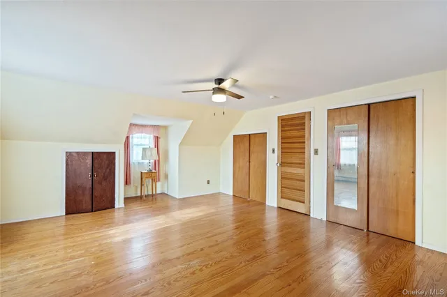 an empty room with wooden floor and a ceiling fan