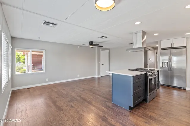 a kitchen with stainless steel appliances granite countertop a sink a stove a refrigerator cabinets and wooden floor