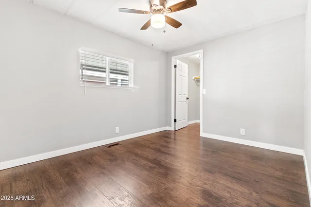 an empty room with wooden floor chandelier fan and windows