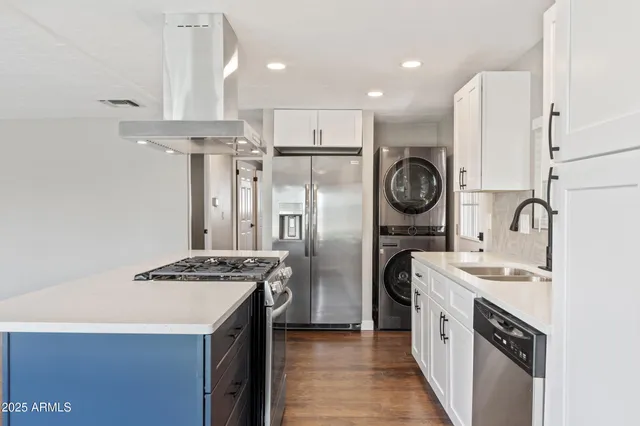 a kitchen with stainless steel appliances granite countertop a sink a stove a refrigerator and island