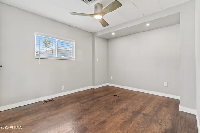 an empty room with a ceiling fan and wooden floor