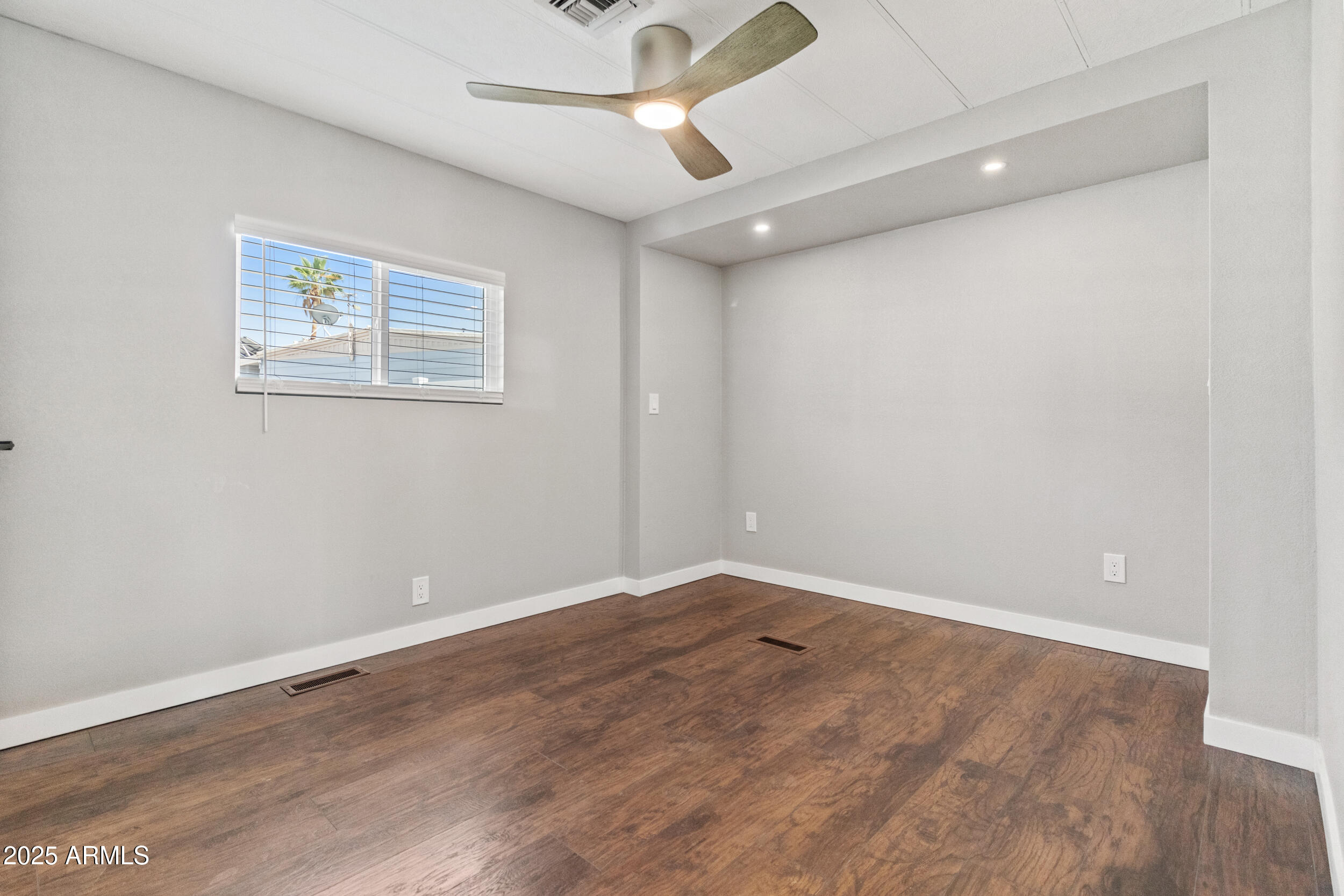 2401 West Southern Avenue, Unit 224 Tempe, AZ 85282 - Photo 23 of 47 an empty room with a ceiling fan and wooden floor
