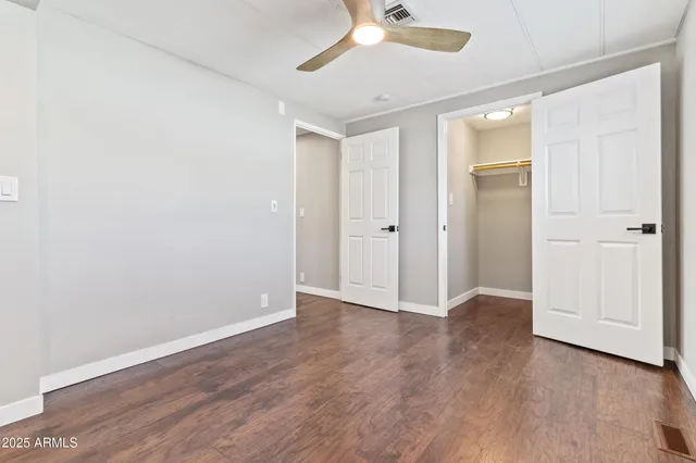 an empty room with wooden floor and a ceiling fan