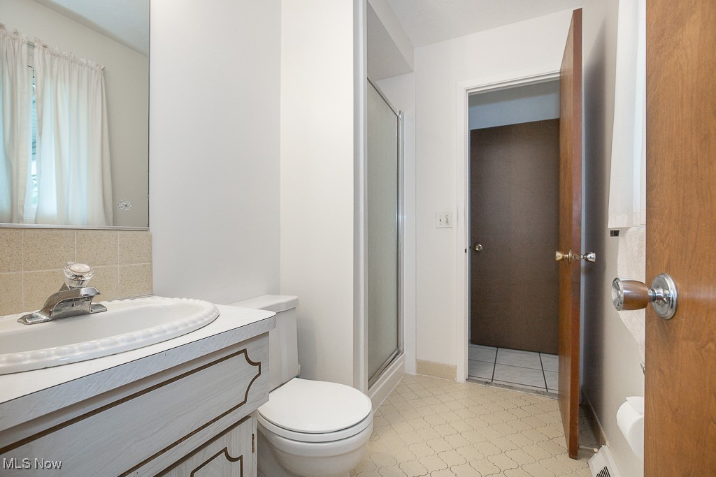4569 McFarland Road Cleveland, OH 44121 - Photo 15 of 29 Full bathroom with a stall shower, backsplash, toilet, and vanity