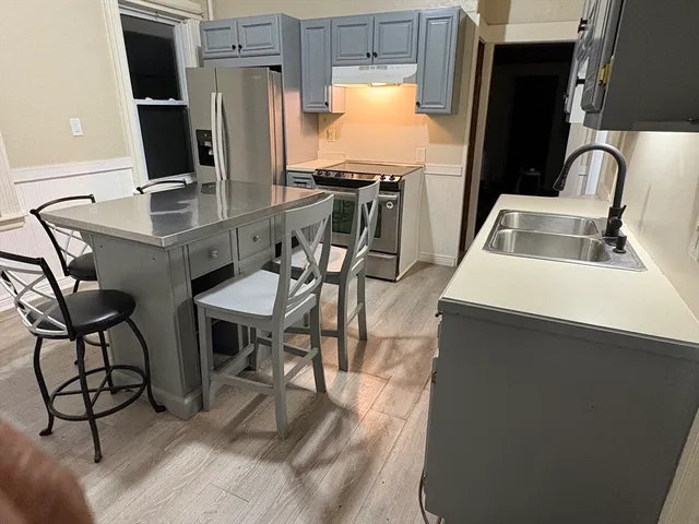 a kitchen with stainless steel appliances a sink stove and table chair