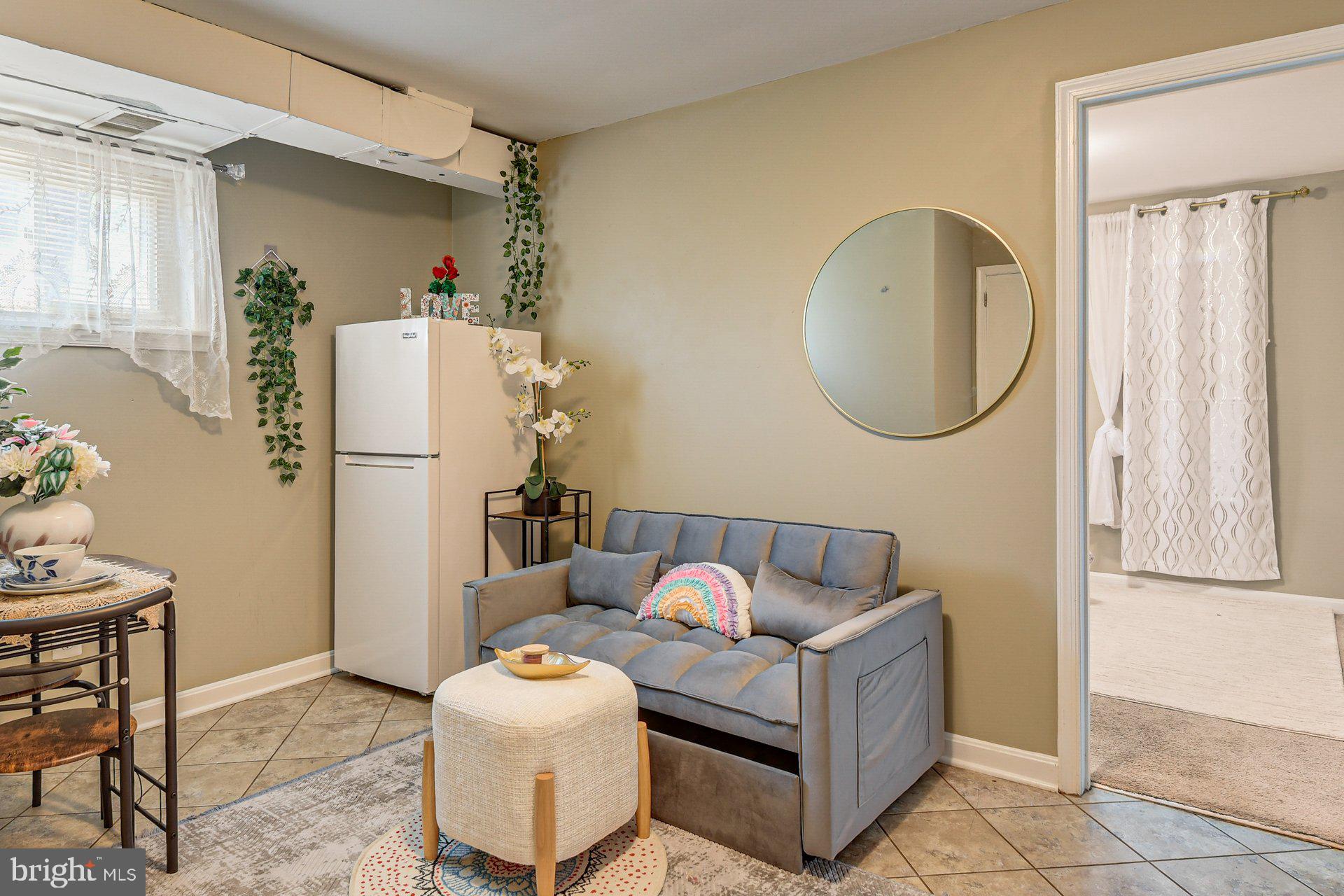 a living room with furniture and a refrigerator