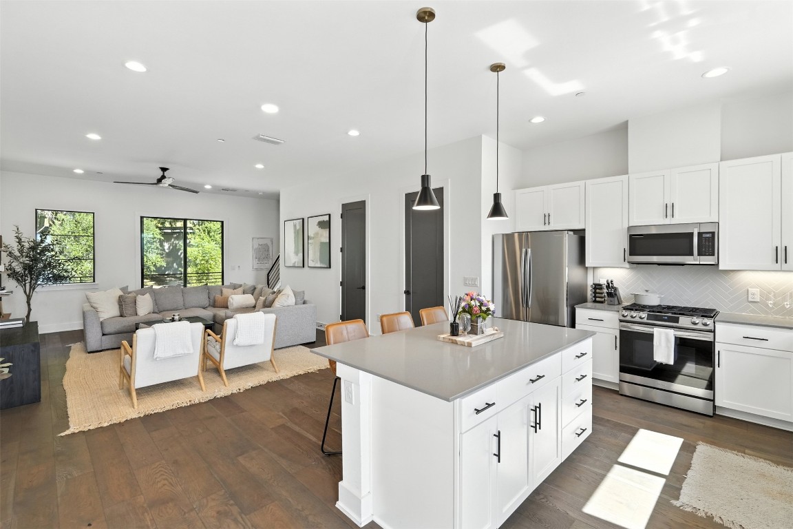 a large kitchen with stainless steel appliances a lot of white cabinets