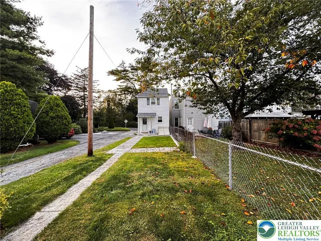 a view of a house with a small yard plants and large tree
