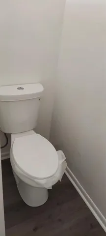 a white toilet sitting next to a white wall