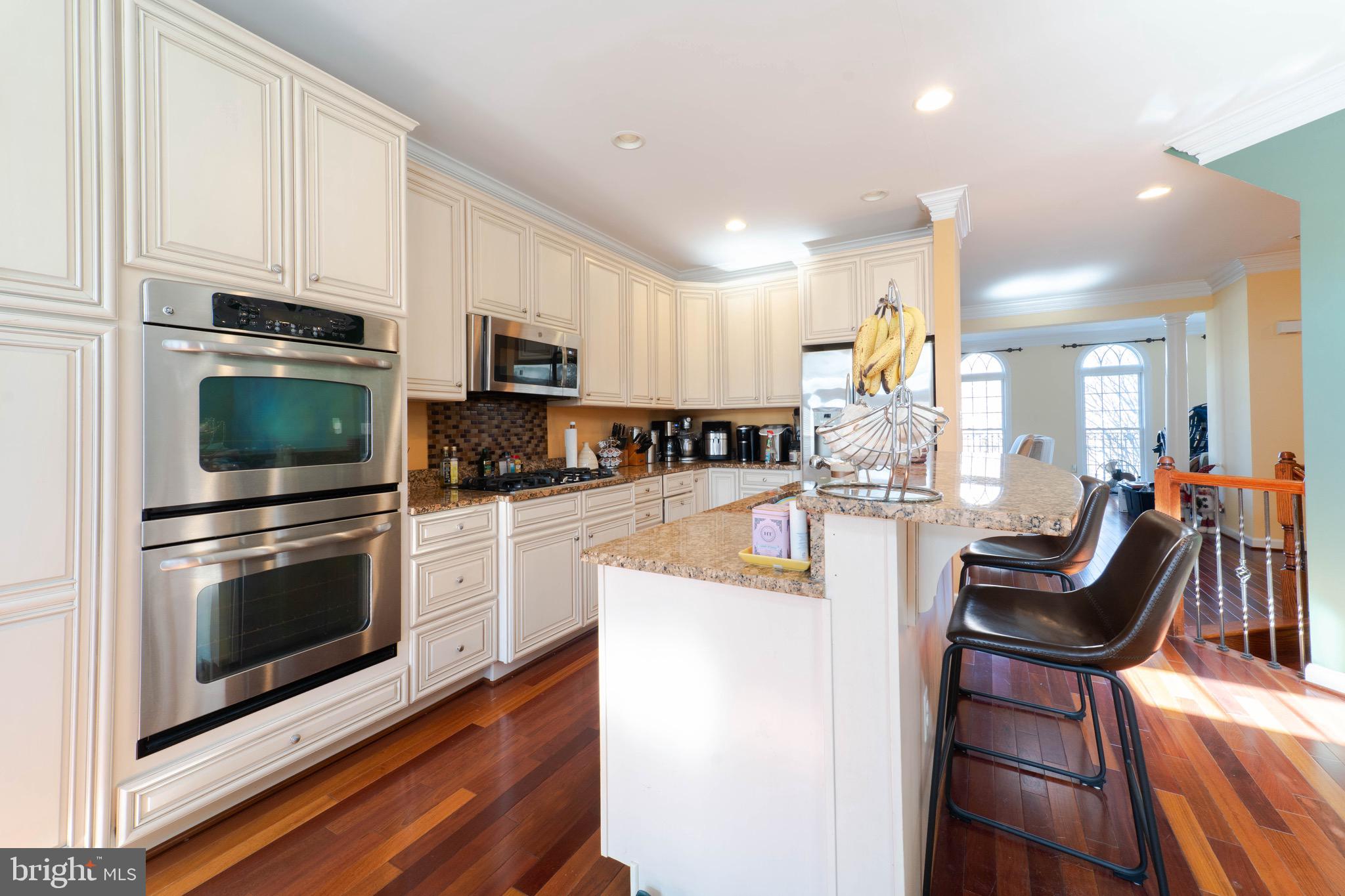 11453 Galliec Street, Unit 40 Fairfax, VA 22030 - Photo 16 of 45 a kitchen with stainless steel appliances kitchen island granite countertop a stove top oven a sink dishwasher a dining table and chairs with wooden floor
