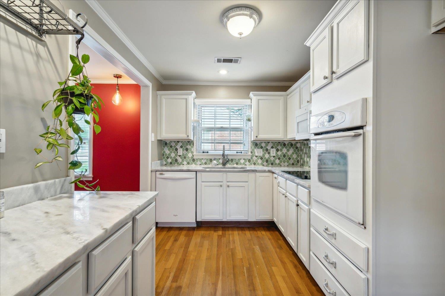 416 Fleda Road Memphis, TN 38120 - Photo 8 of 32 Kitchen with light wood-type flooring, decorative backsplash, ornamental molding, white cabinets, and white appliances