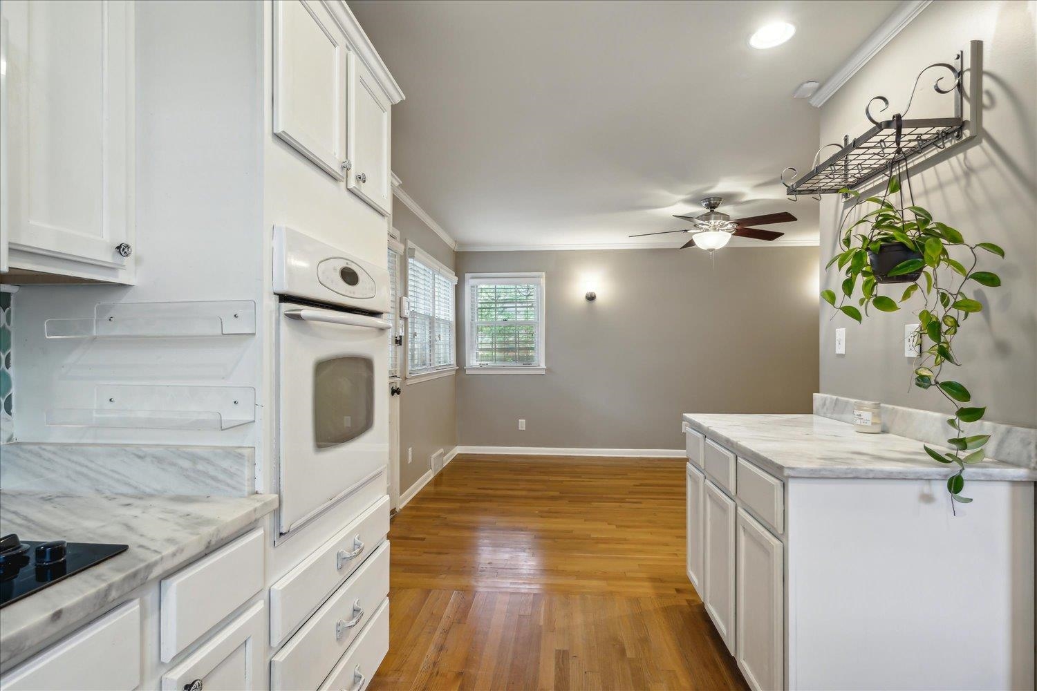 416 Fleda Road Memphis, TN 38120 - Photo 10 of 32 Kitchen featuring ornamental molding, light wood-type flooring, ceiling fan, oven, and white cabinets