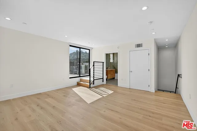 a view of an empty room with a window and wooden floor