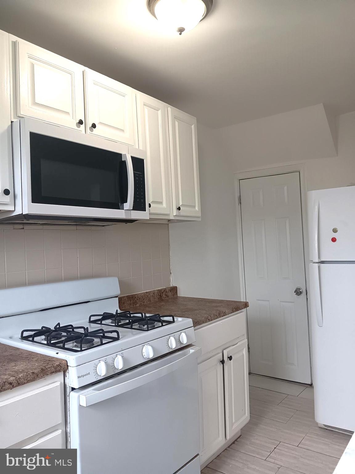 1815 Penfield Street Philadelphia, PA 19126 - Photo 6 of 11 a kitchen with stainless steel appliances a stove a microwave and white cabinets